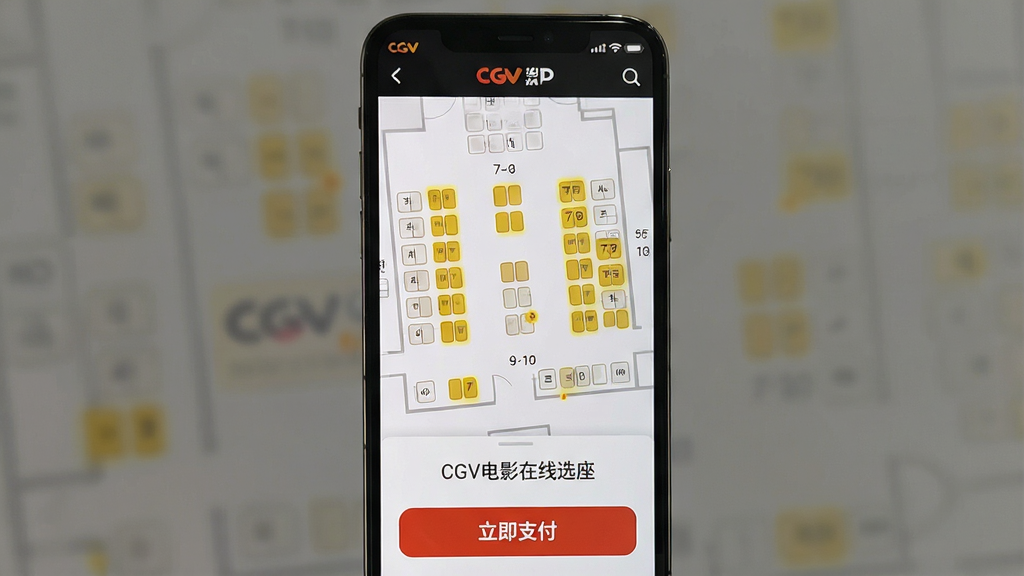 一张智能手机屏幕展示CGV电影APP选座界面,界面清晰显示影院座位图布局,部分座位高亮为可选的黄色,下方有立即支付按钮,整体界面简洁现代,配图文字“CGV电影在线选座”,画质干净,无多余元素。